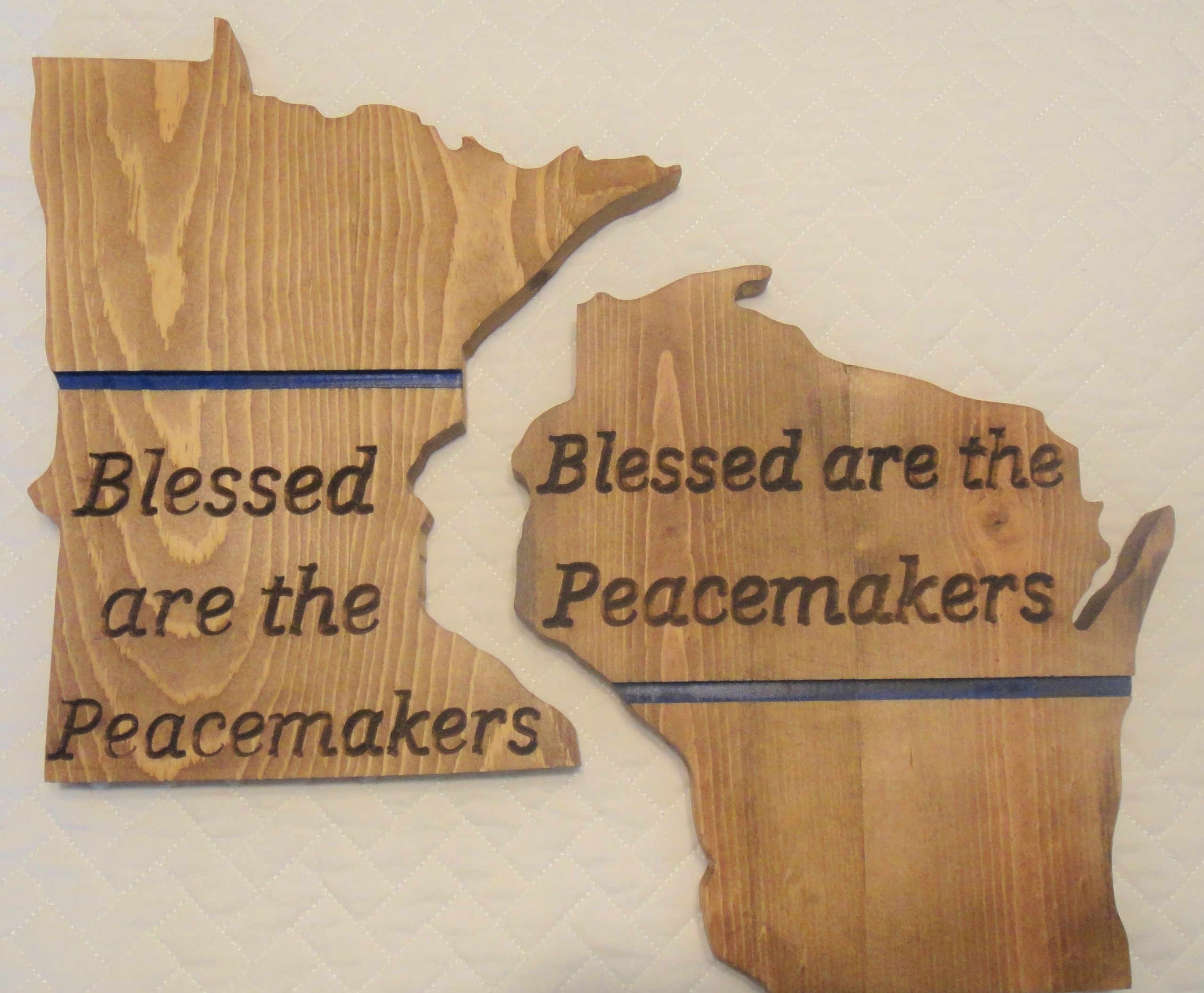 Picture of wooden Wisconsin and Minnesota states with the message Blessed are they Peacemakers and a thin blue line.