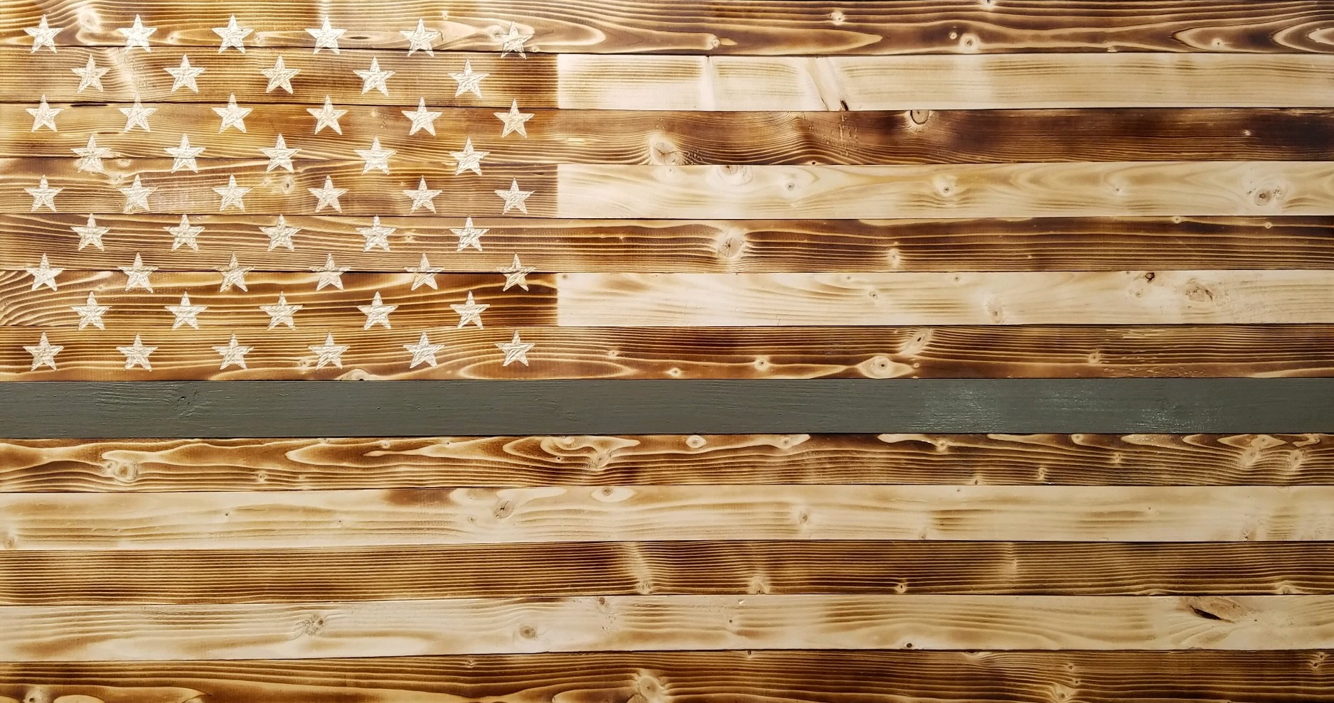 Picture of rustic, wooden flag with green stripe.