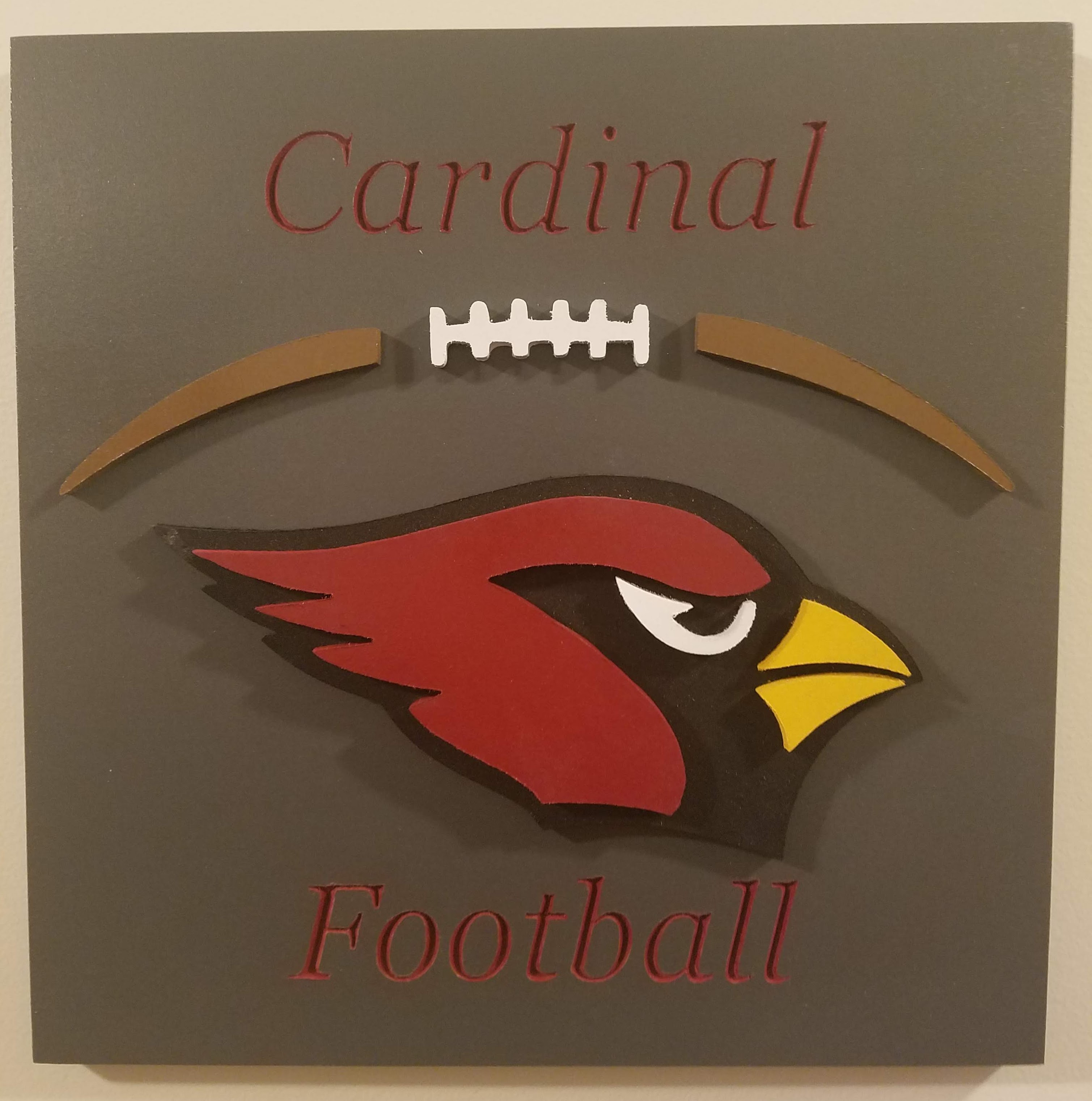 Picture of wooden cardinal football sign with raised cardinal head and football laces.