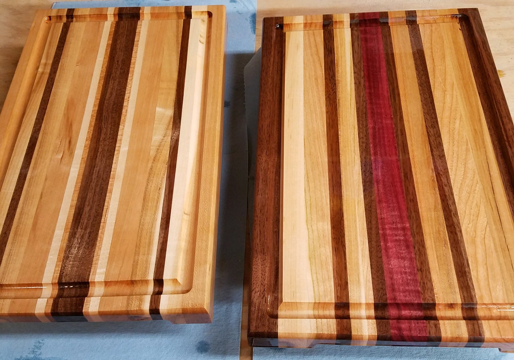 Picture of wooden cutting board. Picture is taken from an angle to show the grain detail of the woods used to create the board.