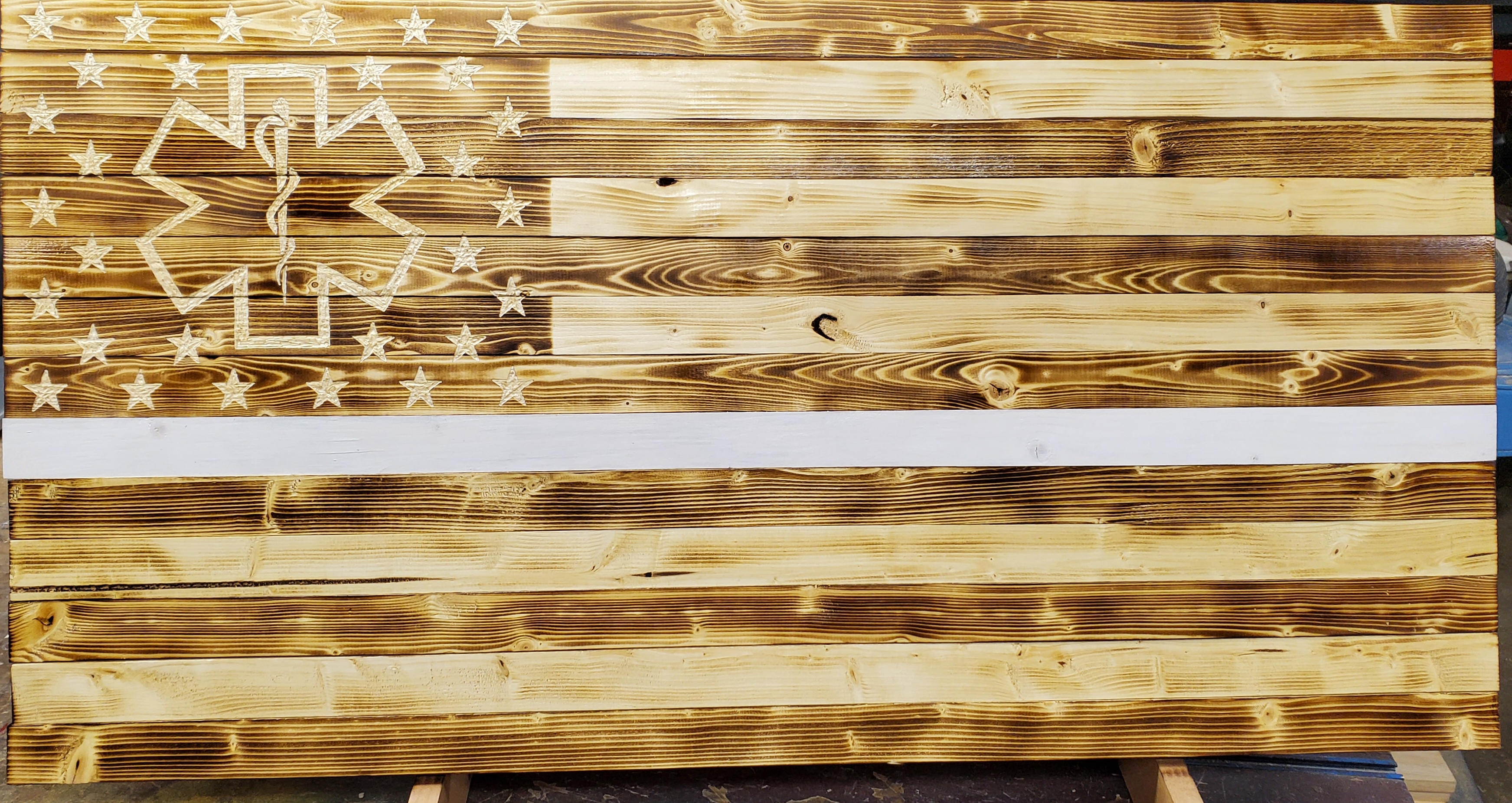 Picture of rustic, wooden flag with white EMS stripe.