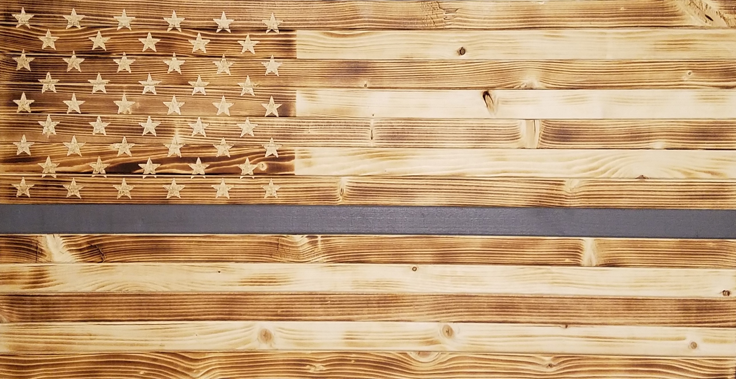 Picture of rustic, wooden flag with gray stripe.