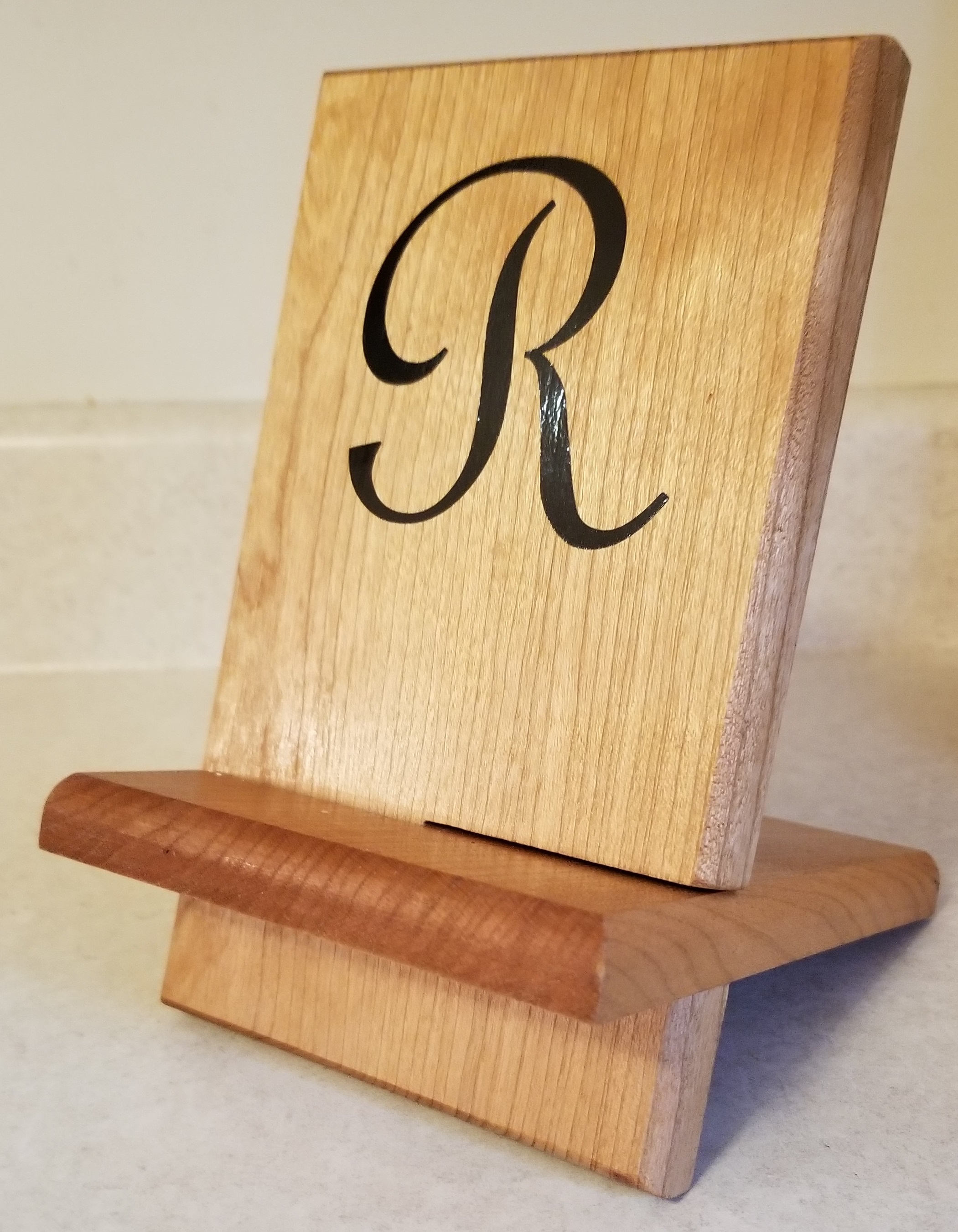 Picture of wooden phone holder stand. The stand has a sticker on the front to represent that they can be customized with any design.