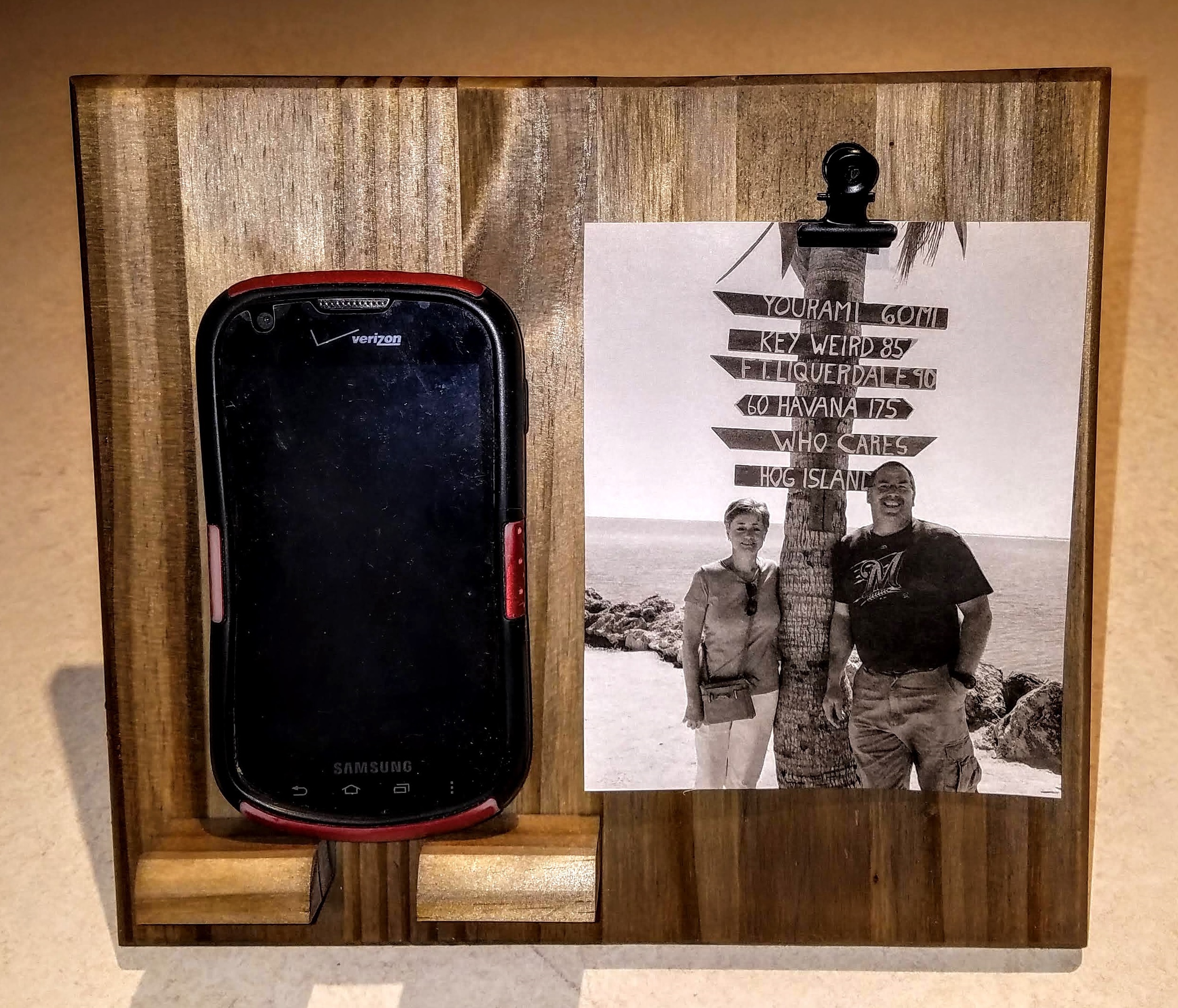 Picture of wooden phone stand holder and has a clip located at the top to hold a picture.